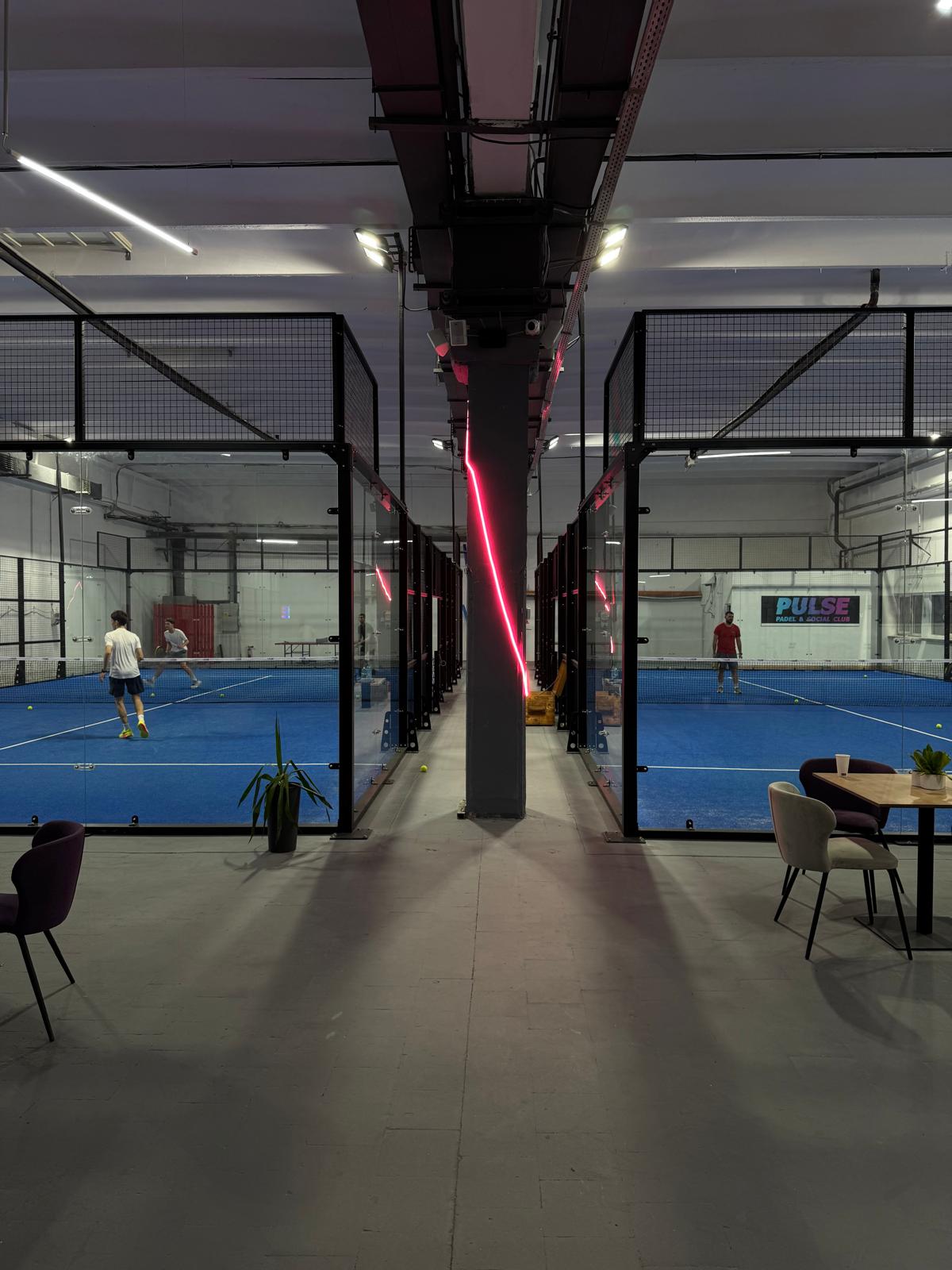 Lounge larg cu mese și logo PULSE neon vizibil în fundal